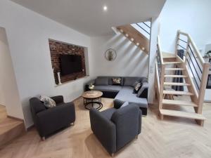 a living room with a couch and a staircase at Le Temps Suspendu in Trémentines