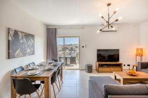 a dining room and living room with a table and chairs at Amazing apartment with pool in Malta in Is-Swieqi