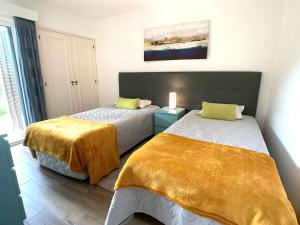 1 Schlafzimmer mit 2 Betten und gelber Bettwäsche in der Unterkunft Detached Villa on Balaia Golf Village with Golf & Tennis, walking distance to Beach and many Bars and Restaurants in Olhos de Água