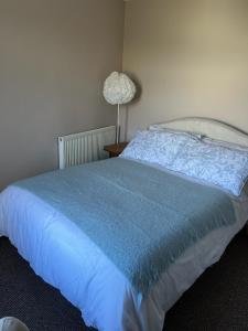 a bedroom with a bed with a blue comforter and a lamp at Katys Cottage, Barnoldswick in Barnoldswick