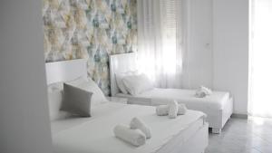 ドゥラスにあるMarina Roomsの白いタオルが敷かれたベッドが2つある白い寝室