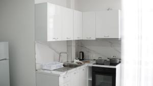 a kitchen with white cabinets and a sink at Marina Rooms in Durrës