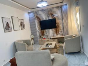 Una sala de estar con dos sillas y un televisor de pantalla plana. en La Gloire House, en Dakar