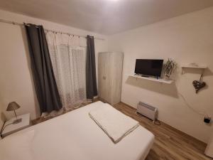 a white bedroom with a bed and a tv at Vavic 2 in Topla +1 photo