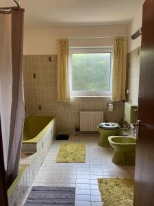 y baño con bañera verde, aseo y lavamanos. en Küstenbude große Auszeit, en Grömitz