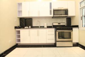 a kitchen with white cabinets and a microwave at Afriqpnb RAP Studio 102 avec Piscine in Douala