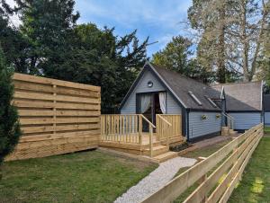 een achtertuin met een houten hek en een huis bij Cear 2- Private Hot Tub- Perth-Pet Friendly Lodge in Almondbank