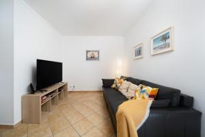 a living room with a black couch and a flat screen tv at Casa Rapp in Alvor