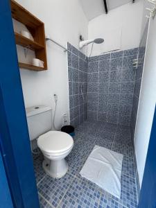 a blue tiled bathroom with a toilet and a shower at Guaecá Hostel - Cumuruxatiba in Cumuruxatiba