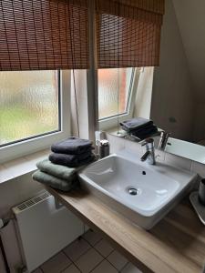 a bathroom sink with towels on a wooden counter at Christiansand in Norddorf
