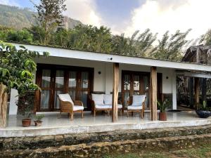 a porch of a house with chairs and trees at Blackwoods FarmHouse in Beragala
