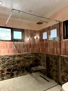 a bathroom with a shower with a glass wall at Blackwoods FarmHouse in Beragala +14 photos