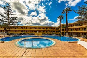 Studio in Los Cristianos front of the beach with pool and WiFi في أرونا: حمام سباحة أمام مبنى
