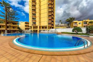 Studio in Los Cristianos front of the beach with pool and WiFi في أرونا: حمام سباحة كبير أمام مبنى