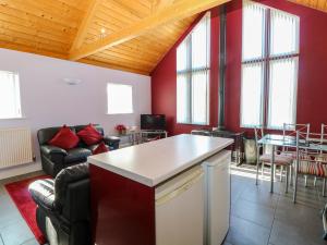 Il comprend une cuisine et un salon avec des murs rouges et une table. dans l'établissement Rookyard Cottage, à Halesworth