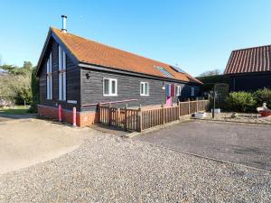 une maison noire avec une clôture en bois devant elle dans l'établissement Rookyard Cottage, à Halesworth