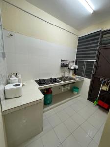 een kleine keuken met een spoelbak en een fornuis bij Qisa Guesthouse 03 in Arau