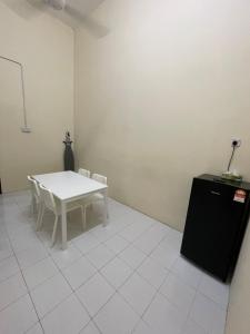 een witte tafel en stoelen in een kamer met een tafel en een koelkast bij Qisa Guesthouse 03 in Arau