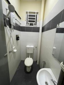 a bathroom with a toilet and a sink at Qisa Guesthouse 03 in Arau +2 photos