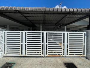 a white gate in front of a building at Qisa Guesthouse 03 in Arau