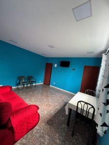a living room with a red couch and a blue wall at Quarto Triplo Solteiro in Barueri