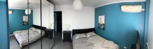 a blue bedroom with two beds and a mirror at Apartament Langa Plaja Diana in Mangalia