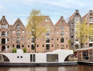 un barco en un canal frente a los edificios en Cozy Cabin at houseboat, en Ámsterdam