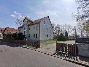 een wit huis met een hek naast een straat bij Pension Leipzig Ost in Borsdorf