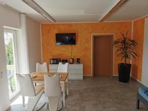 a dining room with a wooden table and white chairs at Pension Leipzig Ost in Borsdorf