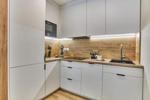a kitchen with white cabinets and a sink at Forest Apartment in Pobierowo