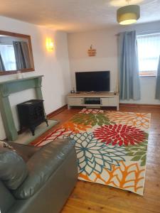 a living room with a couch and a flat screen tv at Cilgerran - cosy cottage in Cilgerran
