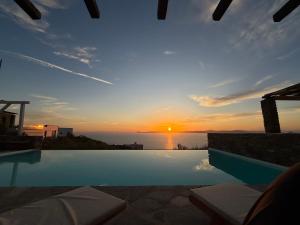 a swimming pool with a sunset in the background at Villa kèalite in Melissaki