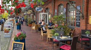 uma rua com pessoas sentadas em mesas em um restaurante em Wohnung am Fischereihafen Modern & gemütlich em Bremerhaven