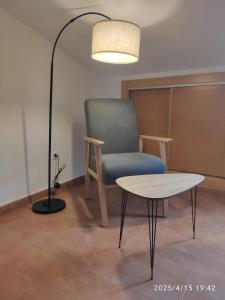 Habitación con silla, mesa y lámpara en Apartamentos Joli, en Olivares de Duero