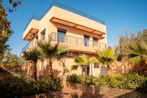 a building with palm trees in front of it at Villa Park Marrakech in El Aggada