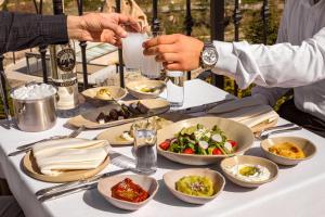 a table with plates of food and a person holding a wine glass at Zafora Cave Suites Hotel Cappadocia in Uçhisar