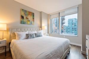 Un dormitorio con una cama blanca con una ventana. en Luxury Apt with Balcony In Seaport, en Boston