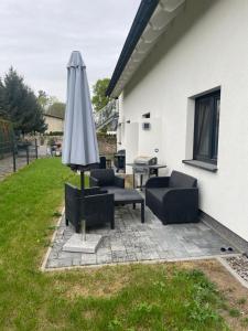 a patio with an umbrella and chairs and a table at Großkoschen Wohnungen in Senftenberg