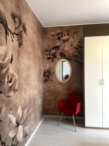 a room with a red chair and a mirror at Helle, gemütliche Wohnung in Sommer-Freibadnähe in Origgio