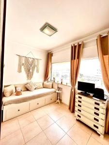 a living room with a couch and a tv and a window at T1 na 1 linha da Praia da Rocha in Portimão