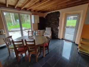 a dining room with a table and chairs and a stone wall at La Catiche in Bastogne