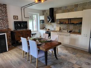 a kitchen with a wooden table and white chairs at Atelier du chateau in Feings