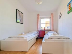 two twin beds in a room with a window at Silbermöwe in Greetsiel
