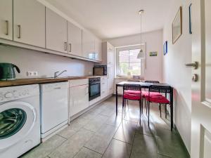 a kitchen with a washing machine and two stools at Silbermöwe in Greetsiel