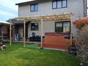 a wooden pergola in front of a house at Eagles View in Llanrwst