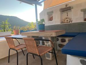 een patio met 2 stoelen, een tafel en een klok bij Aloe House in Patmos