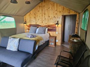 a bedroom with a bed and a chair in a room at Kolobe Luxury Glamping Safari Tent in Fochville