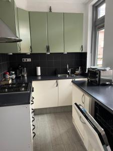 a kitchen with white cabinets and a black counter top at Slapen bij Bartje in Assen