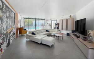 ein Wohnzimmer mit einem weißen Sofa und einem Fernseher in der Unterkunft Villa haut de gamme avec Piscine, Bar et Cinéma in Pierre-Levée + 212 Fotos