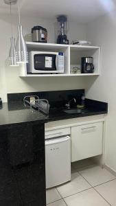 a kitchen with a counter top with a microwave at Flat Village - Aldeia das Águas C202 in Barra do Piraí